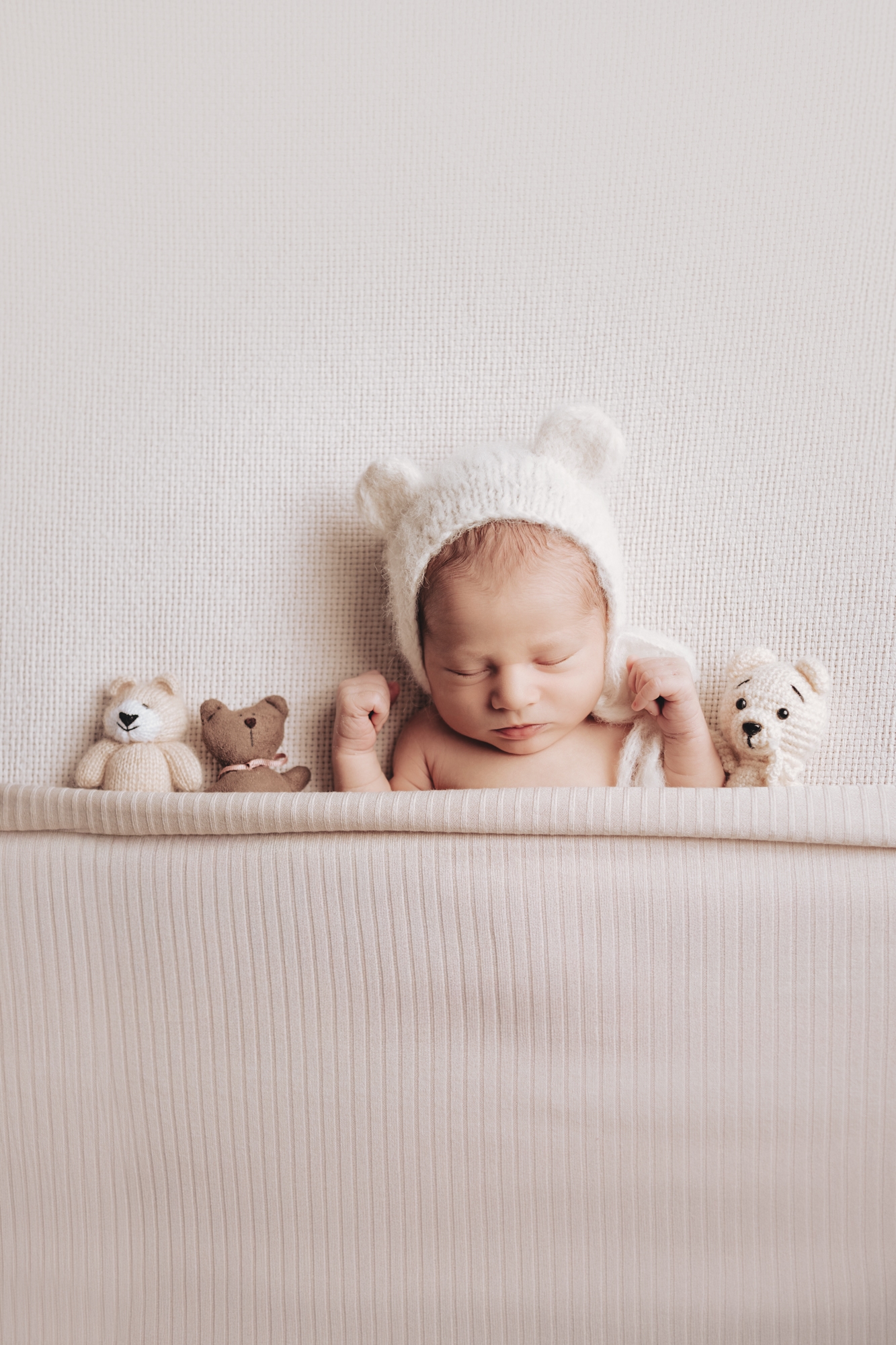 Schlafendes Neugeborenes mit vielen Kuscheltieren beim Newbornshooting in Wien