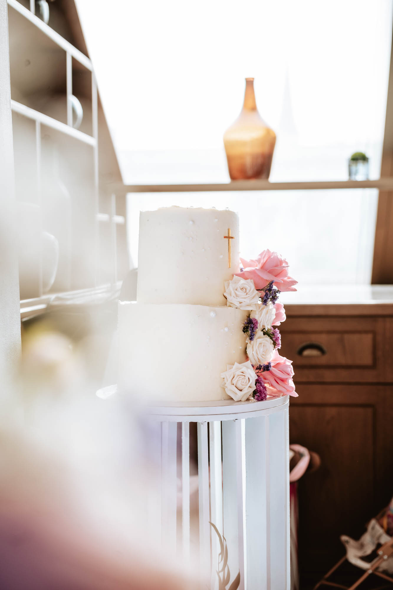 Weiße, mehrstöckige Tauftorte mit floraler Dekoration.