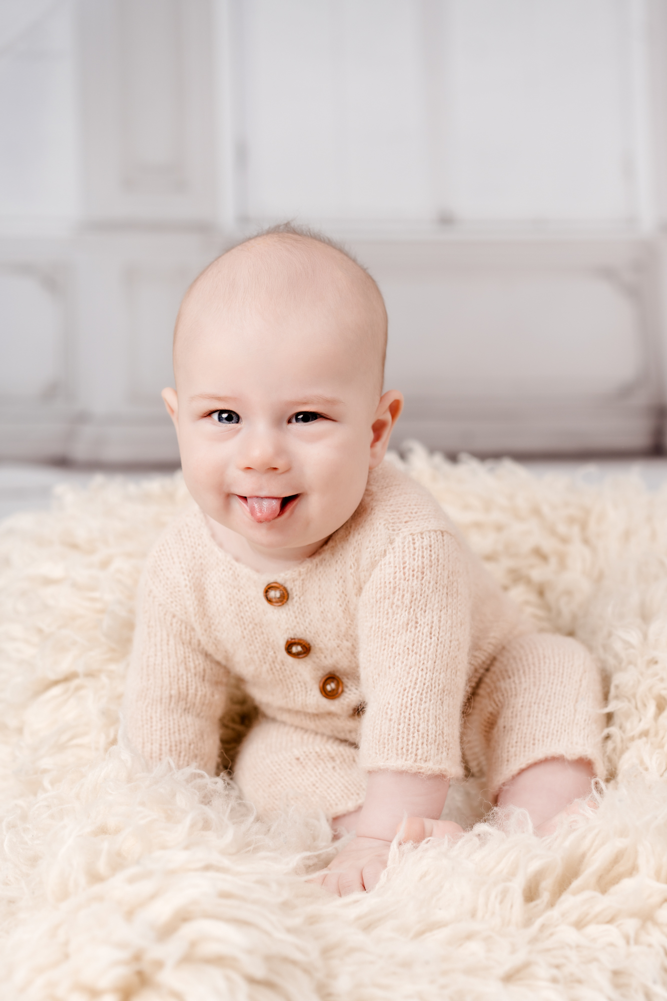 Meilenstein Shooting Wien: Sitter Session mit Baby in beigem Strick-Outfit auf weichem Teppich sitzend