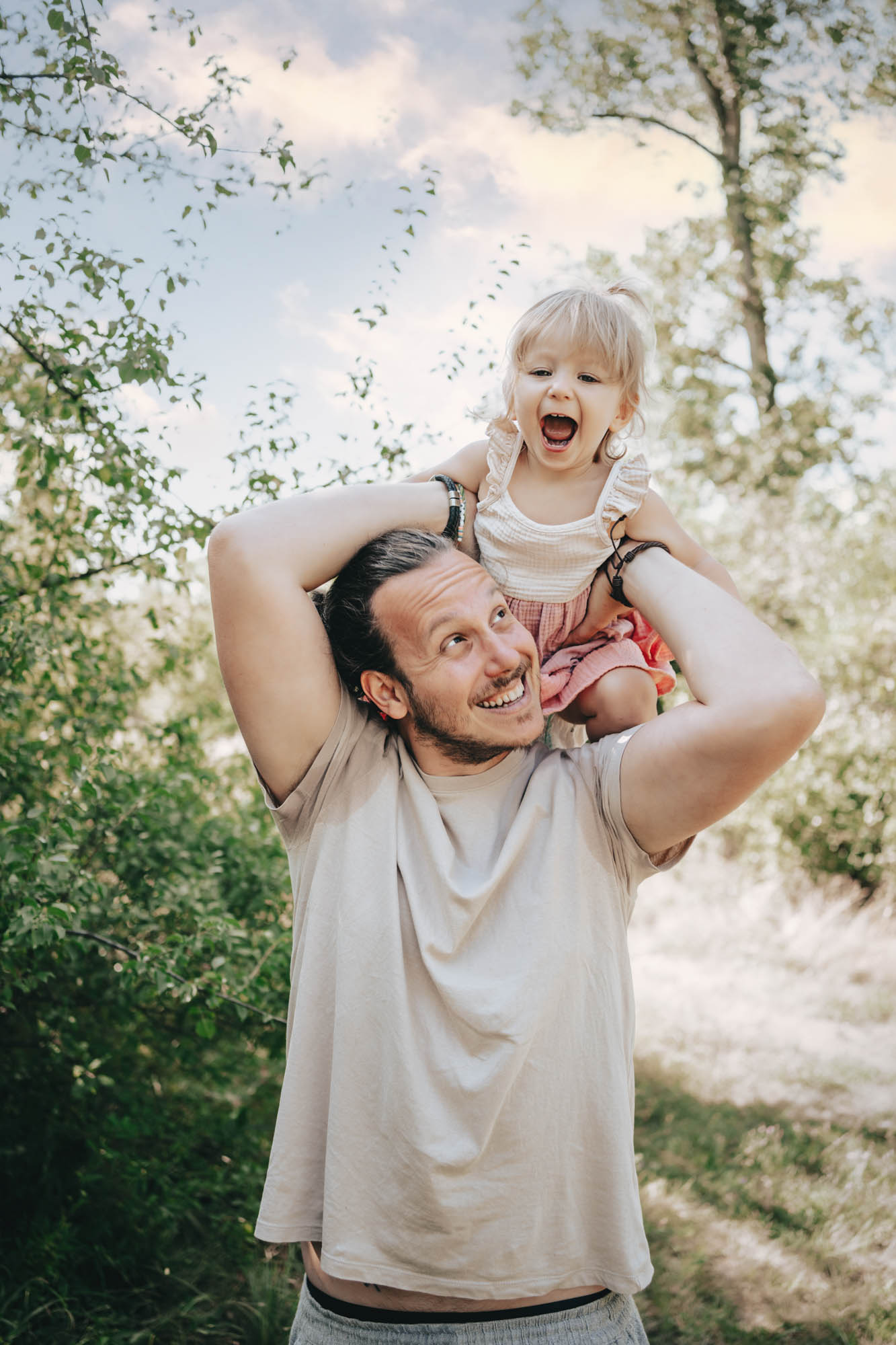 Vater tr&auml;gt lachendes Kind auf den Schultern im Wald.