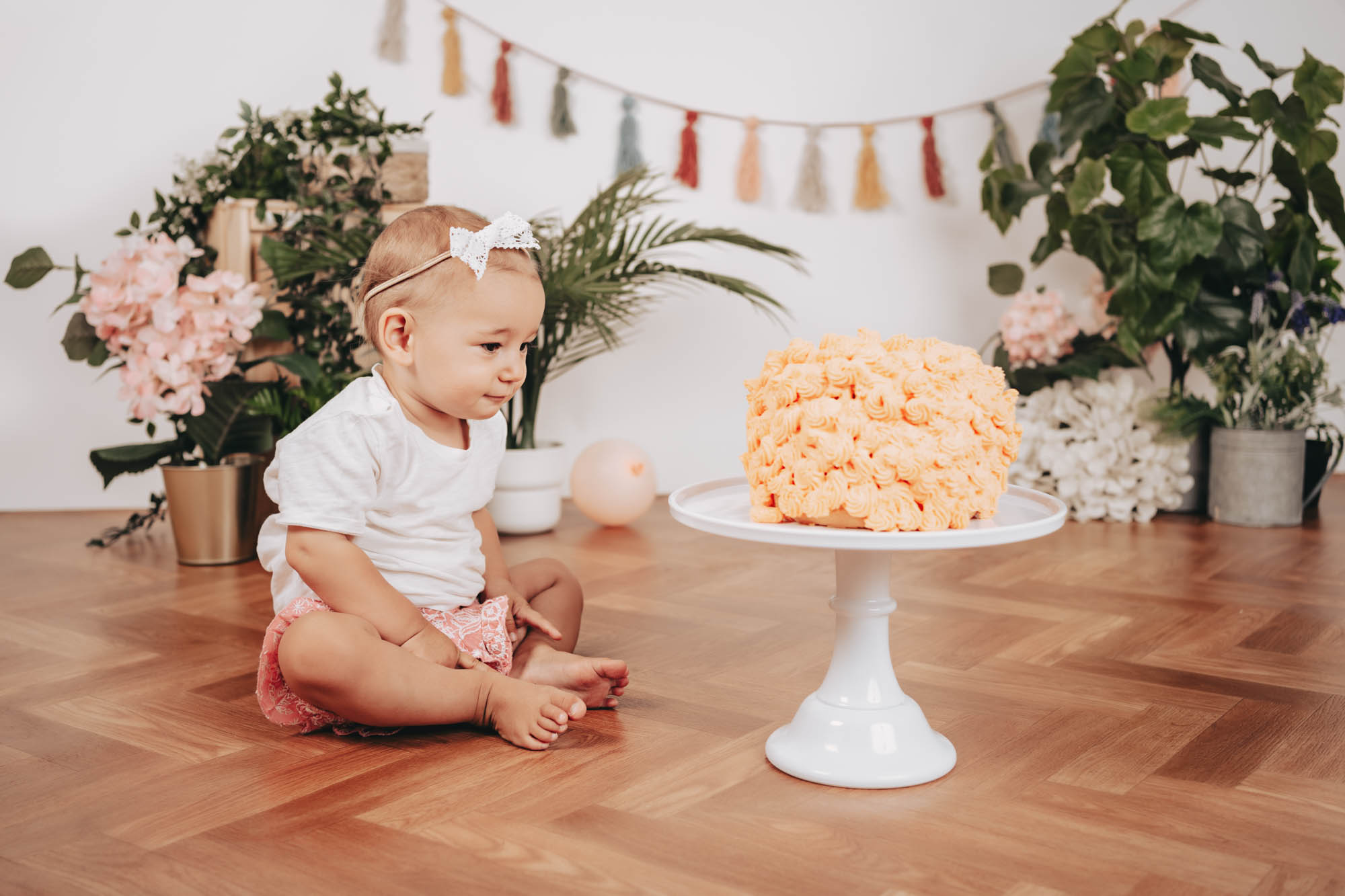 Kind ber&uuml;hrt vorsichtig eine bunte Torte bei einem Cake Smash Shooting in Wien.