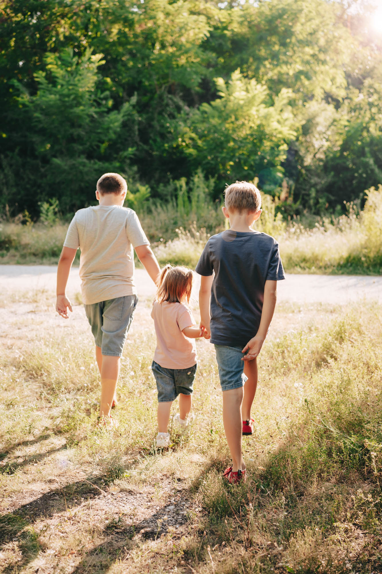 Zwei Kinder laufen Hand in Hand einen sonnigen Weg entlang.